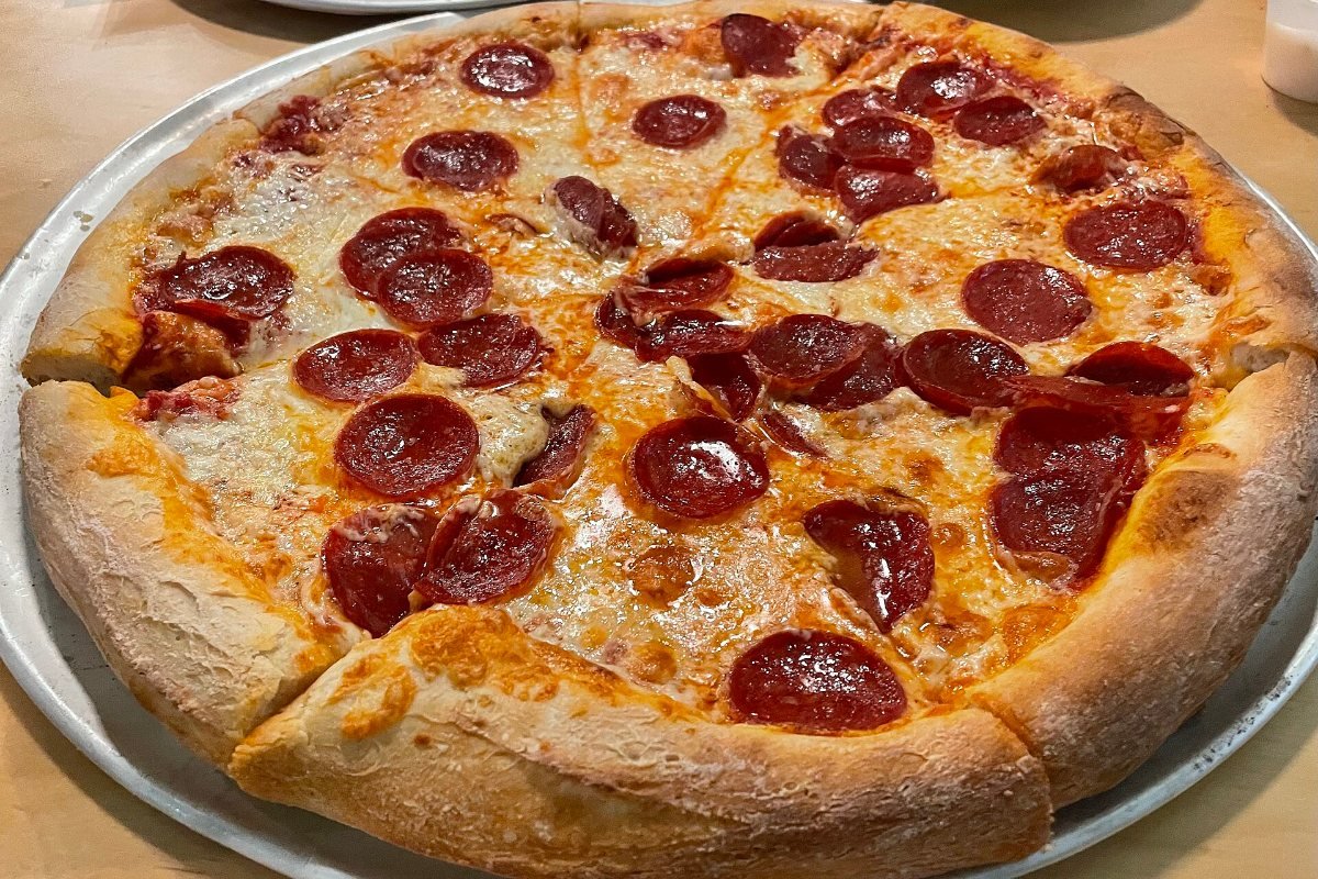 A whole pepperoni pizza on a metal tray.