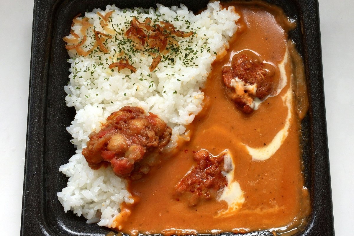 Butter chicken curry and white rice in a takeaway tray.