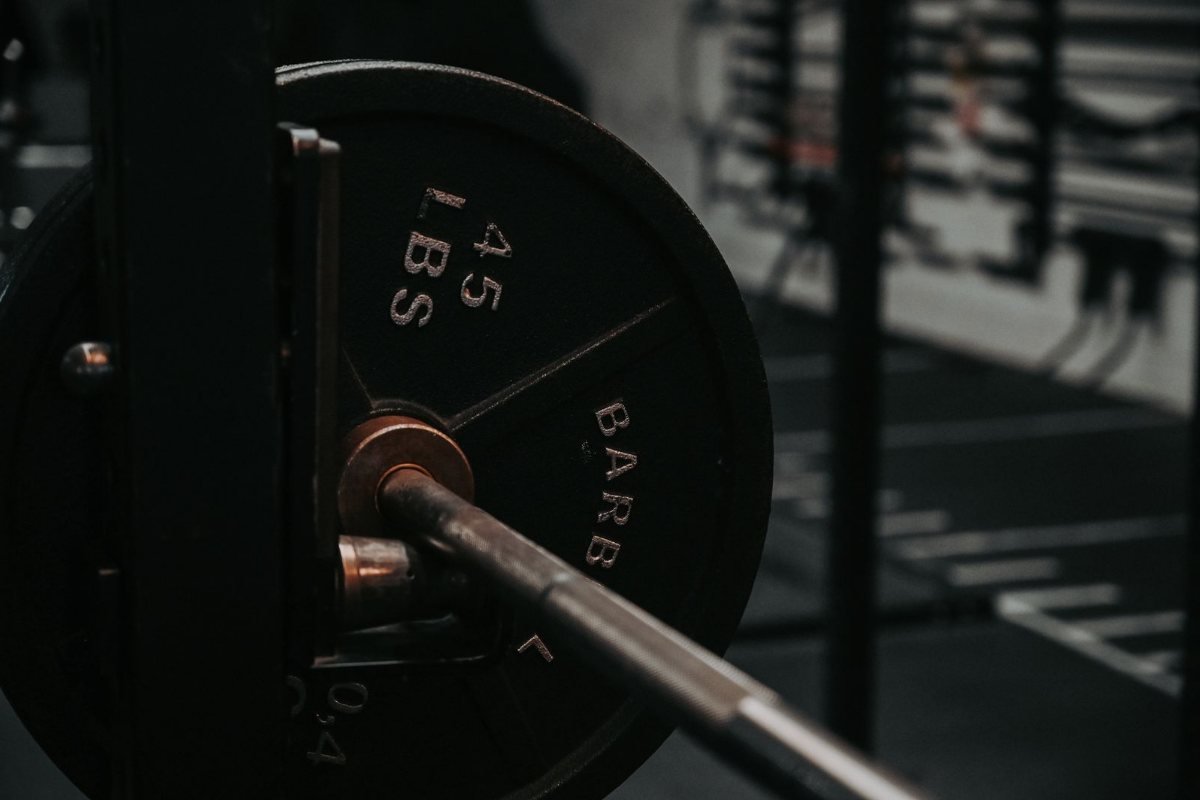 A barbell loaded with a 45 lb plate in a dim gym.