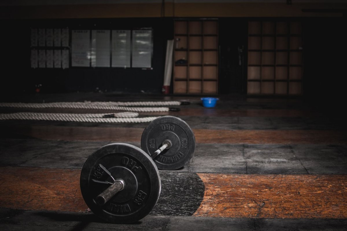 A barbell with plates on a wooden gym floor.