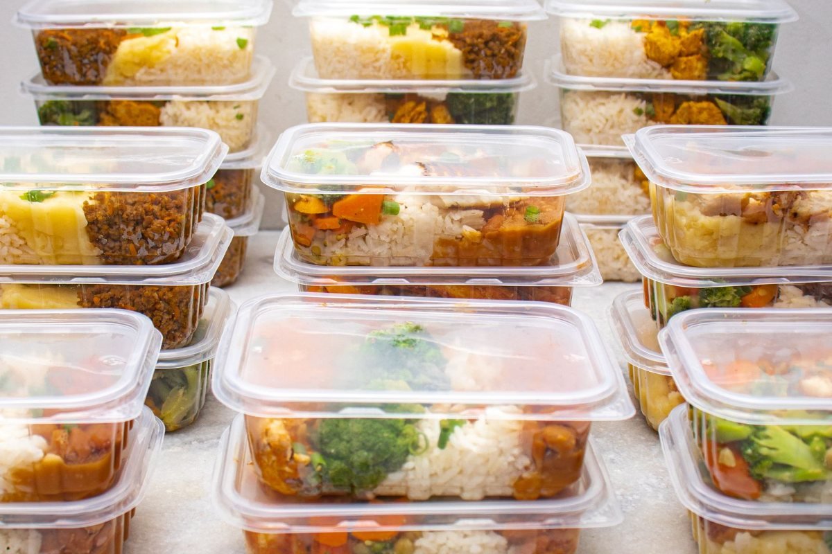 Rows of meal-prep containers filled with rice and vegetables.