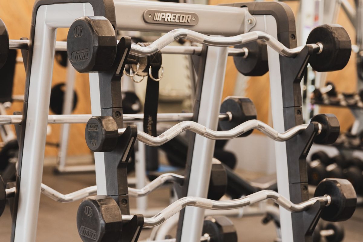 Rows of dumbbells on a three-tier rack in a gym.