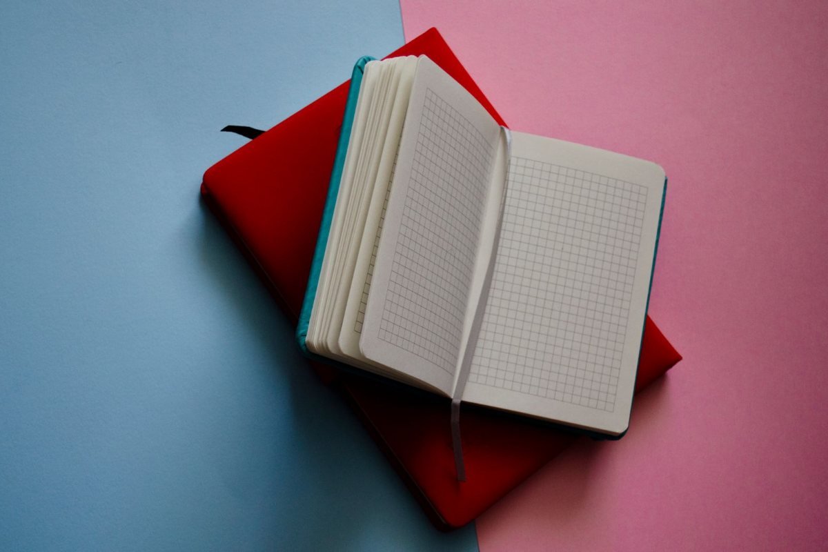An open grid-paper notebook on a pink and blue surface.