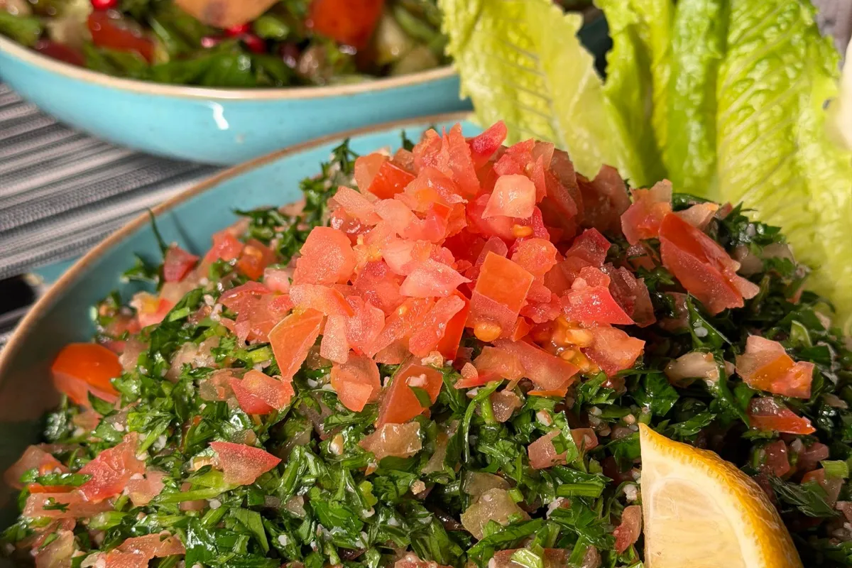Bowls of Lebanese tabbouleh and fattoush with a lemon wedge.