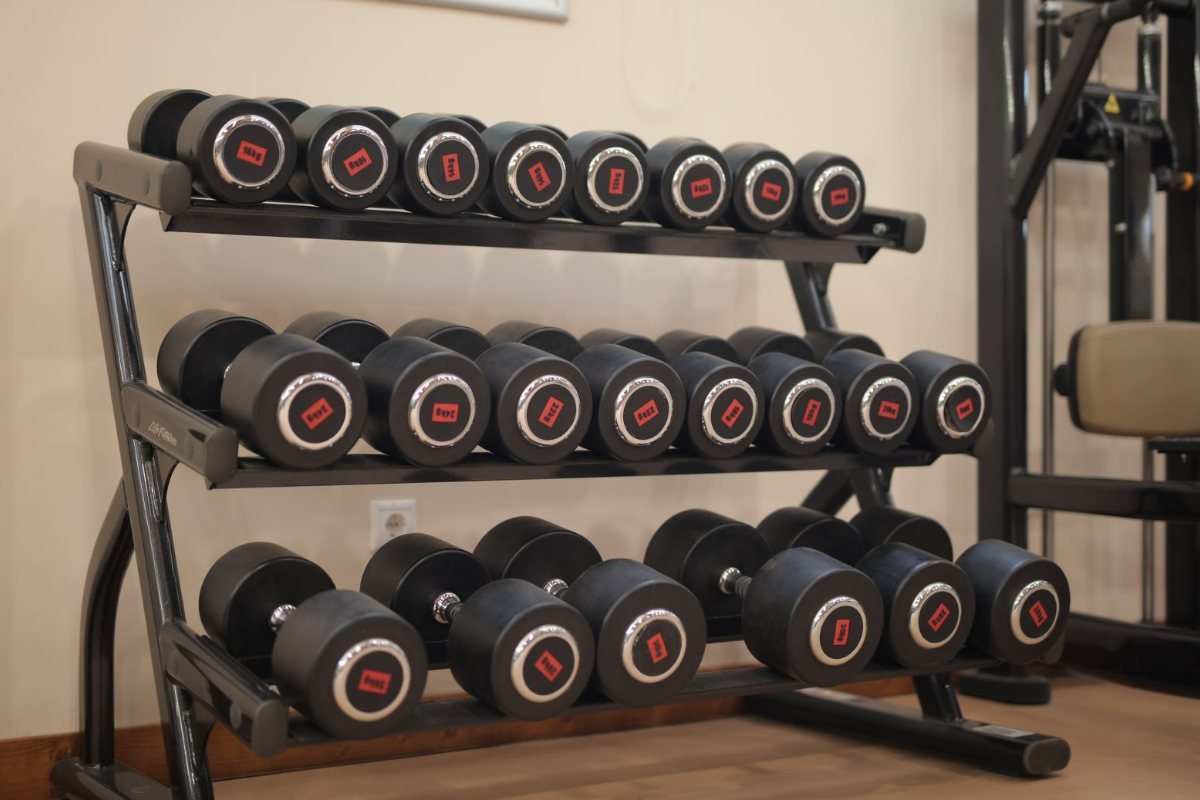 A rack of black and red dumbbells in a gym.