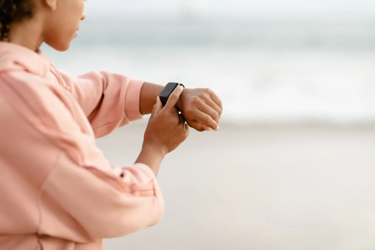 A woman checking her watch beside the sea.