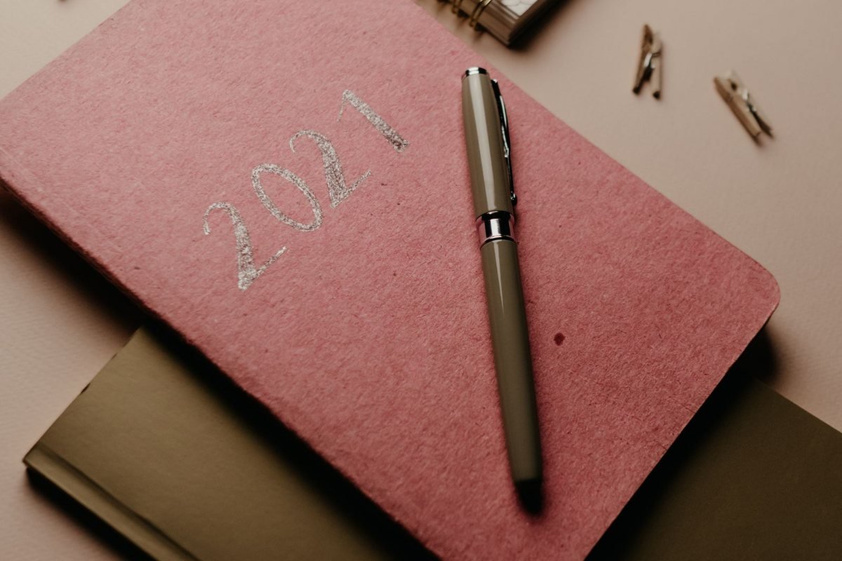 A planner, notebooks and a pen on a table.
