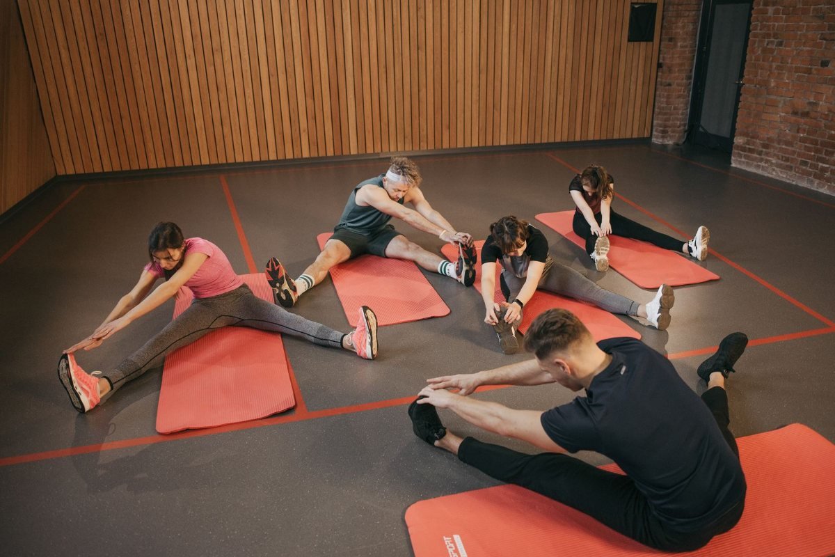 Adults stretching on exercise mats in a wood-panelled studio class.