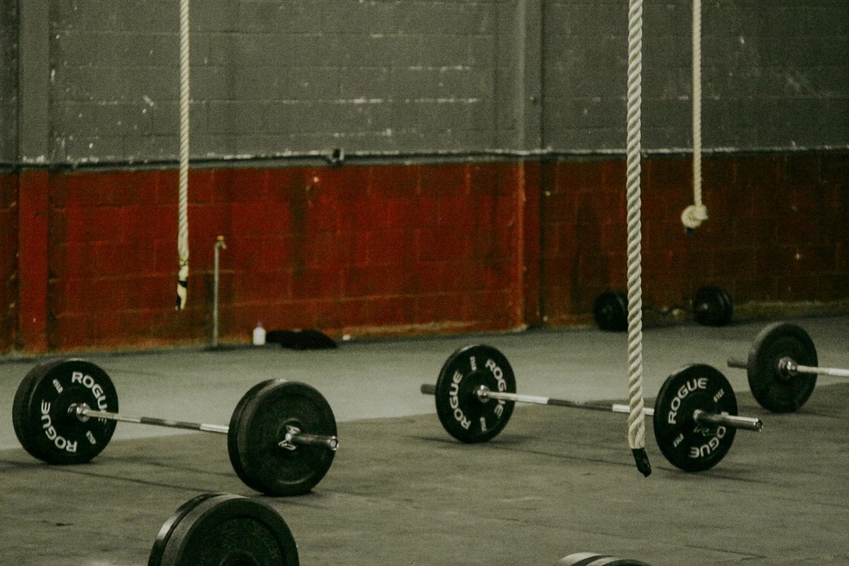 Barbells on the floor of an industrial-style gym.